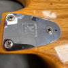 Close-up of Music Man guitar chrome neck plate with logo on natural wood finish guitar body