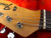 Close-up of Fender guitar wooden headstock with tuning pegs and metal strings on red background
