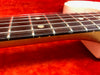 Close-up of electric guitar fretboard with metal frets and steel strings on red background