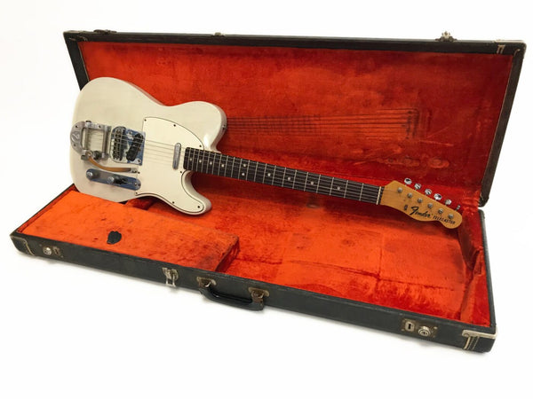 Vintage Fender Telecaster electric guitar in white finish with Bigsby vibrato tailpiece, displayed in open black hard case with orange plush interior