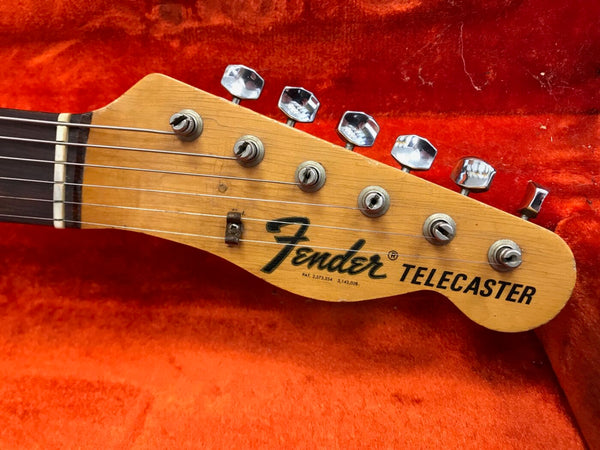 Close-up of Fender Telecaster guitar headstock with tuning pegs and strings on red velvet background