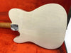 Back view of white electric guitar body with wood grain finish inside orange-lined guitar case