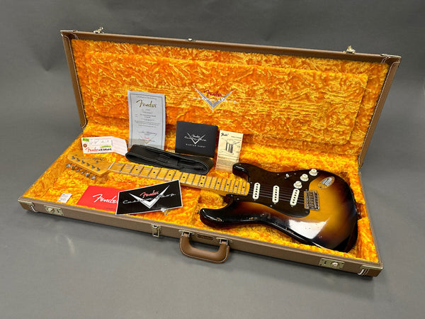 Fender Custom Shop vintage sunburst Stratocaster electric guitar in open brown case with orange plush interior, including certificate of authenticity and Fender accessories