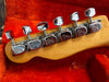 Close-up of six chrome Fender tuning pegs on maple guitar headstock resting on orange plush case lining