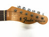 Close-up of vintage Fender Telecaster guitar headstock with six tuning pegs and metal strings on white background