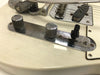 Close-up of vintage white electric guitar chrome control plate with two knurled metal knobs and black toggle switch near bridge pickup and bridge saddles