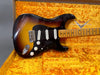 Vintage Fender Stratocaster electric guitar with sunburst finish, maple neck, and white single-coil pickups in yellow plush-lined Fender Hard Case