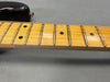 Close-up of maple guitar fretboard with black dot inlays and metal frets on electric guitar neck with black body edge on gray background