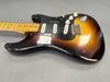 Vintage sunburst electric guitar with maple neck and three single-coil pickups showing wear and scratches on body