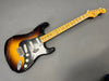 Vintage Fender Stratocaster electric guitar with sunburst finish, maple neck, and black pickguard showing natural wear and aging