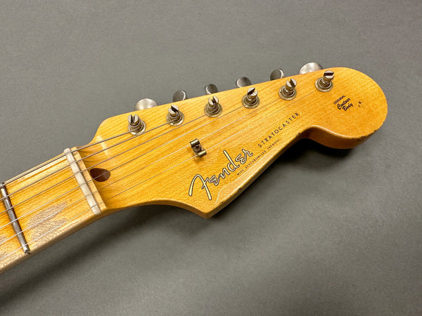Close-up of Fender Stratocaster guitar headstock with vintage tuning pegs on gray background