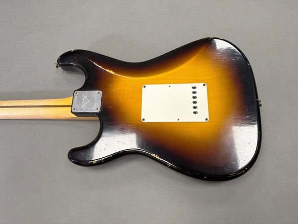 Vintage sunburst electric guitar body with white tremolo cover and maple neck viewed from back showing wear and scratches