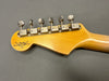 Close-up of Fender Custom Shop guitar headstock with vintage tuning pegs and natural wood finish on gray background