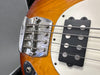 Close-up of vintage electric bass guitar bridge and humbucker pickup on sunburst finish body with white pickguard