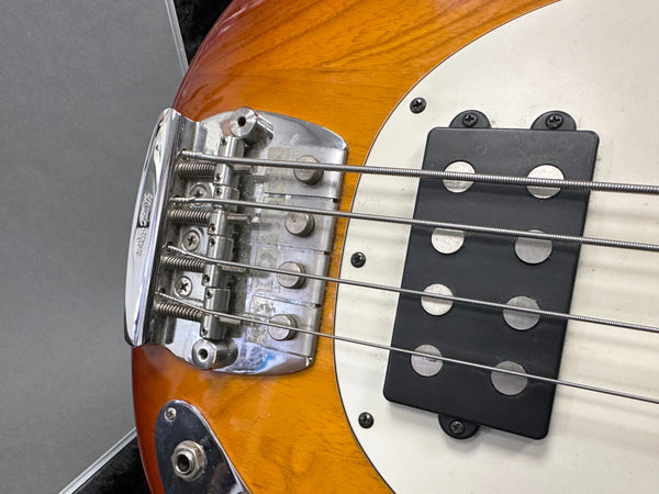 Close-up of vintage electric bass guitar bridge and humbucker pickup on sunburst finish body with white pickguard