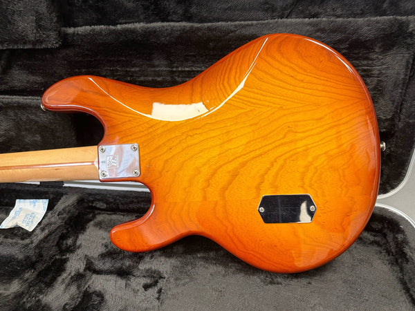 Back view of amber glossy solid body electric guitar with maple neck in black plush lined hardshell case
