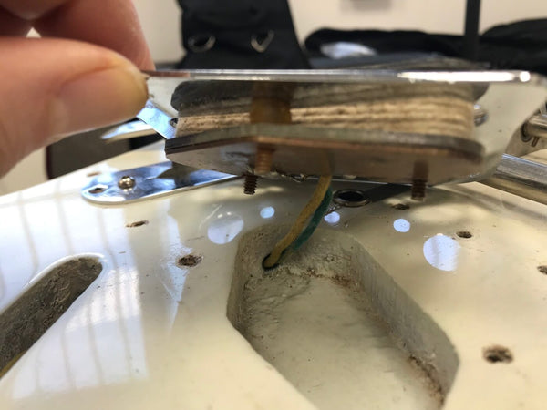 Close-up of vintage white electric guitar pickup removed showing wiring and pickup cavity in guitar body