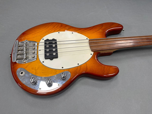 Fretless electric bass guitar with orange sunburst finish and chrome hardware on gray background
