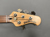 Close-up of Ernie Ball Music Man StingRay bass guitar headstock with tuning pegs and strings on gray background