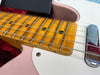 Close-up of electric guitar maple fretboard with metal frets and black dot inlays, white pickguard, and chrome bridge on pink body guitar