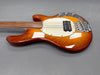 Sunburst finish electric bass guitar with four strings, white pickguard, chrome bridge, and control knobs on gray background