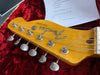 Close-up of vintage Fender Telecaster guitar headstock with tuning pegs and strings on red plush case lining