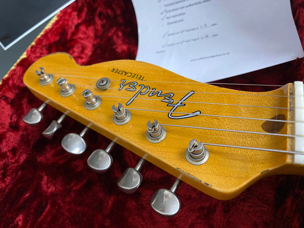 Close-up of vintage Fender Telecaster guitar headstock with tuning pegs and strings on red plush case lining