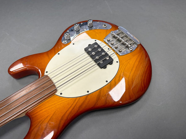 Sunburst electric bass guitar with white pickguard and four control knobs on gray background
