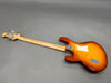 Back view of sunburst electric bass guitar with maple neck and chrome tuning pegs on gray background