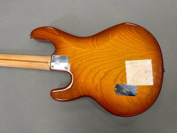 Back view of amber sunburst electric guitar body with visible wood grain and bolt-on maple neck on gray background