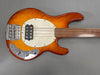 Fretless natural wood finish electric bass guitar with chrome hardware and white pickguard on grey background