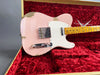 Pink Fender Custom Shop Telecaster electric guitar with relic finish and maple neck resting in red plush-lined guitar case