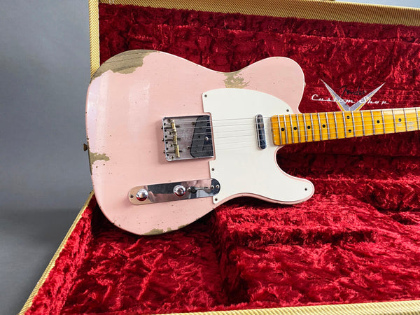 Pink Fender Custom Shop Telecaster electric guitar with relic finish and maple neck resting in red plush-lined guitar case