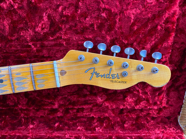 Close-up of Fender Telecaster guitar headstock with tuning pegs and strings on red plush guitar case lining