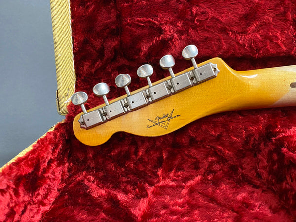 Close-up of Fender Custom Shop guitar headstock with vintage tuners in red plush-lined guitar case