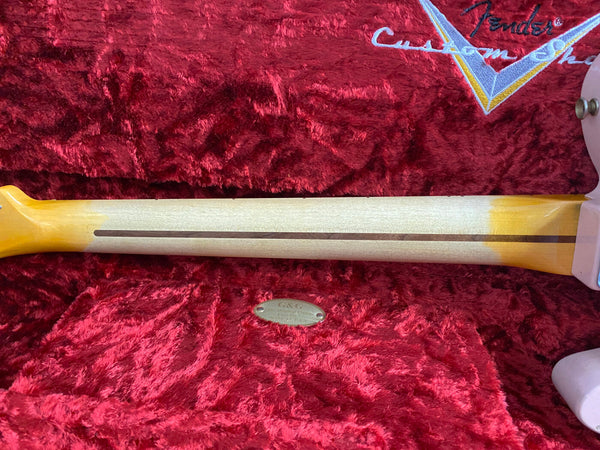 Close-up of Fender Custom Shop guitar neck with skunk stripe on natural wood finish, resting on plush red velvet case interior with Fender Custom Shop embroidered logo.