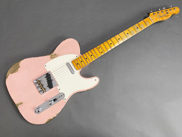 Fender Telecaster electric guitar with worn pink finish, maple neck and fretboard, white pickguard, and chrome hardware against gray background.