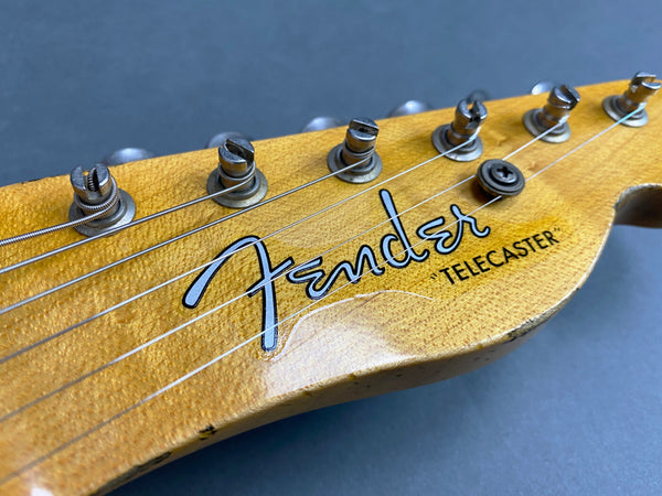 Close-up of Fender Telecaster guitar headstock with tuning pegs and strings against a blue background