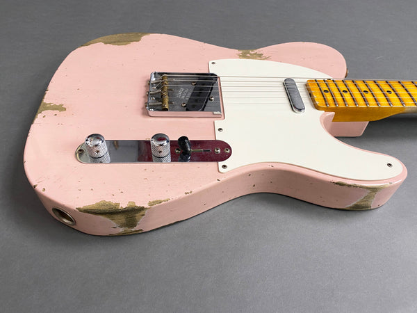 Close-up of vintage pink electric guitar body with white pickguard, chrome bridge, and control knobs showing wear and paint chipping on gray background
