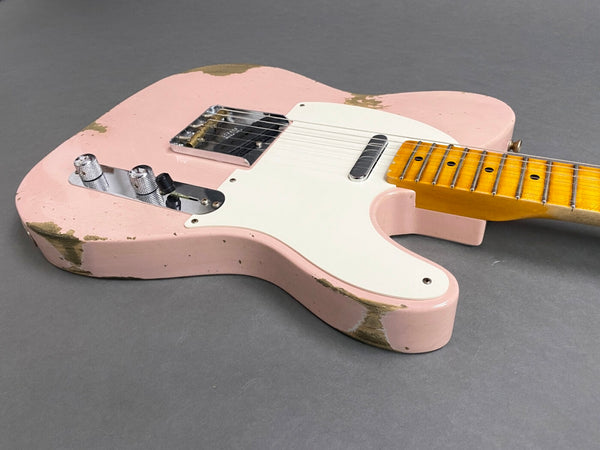 Pink relic electric guitar with white pickguard, chrome control knobs, and maple neck on gray background