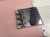 Close-up of vintage Fender Telecaster guitar bridge with brass saddles and single-coil pickup on pink body