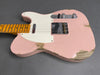 Vintage pink electric guitar with maple neck and white pickguard, showing worn paint and relic finish on gray background