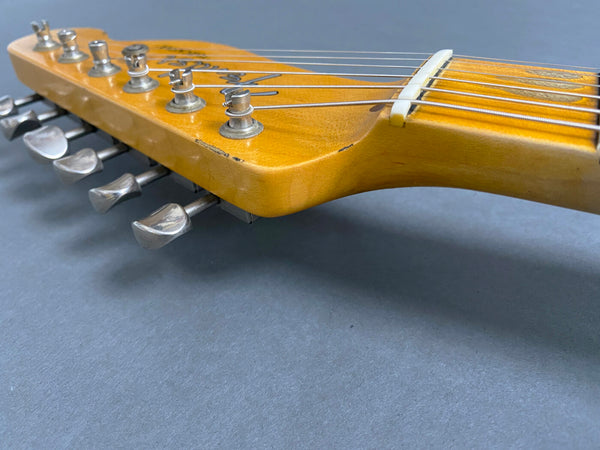 Close-up of vintage Fender Telecaster guitar headstock with tuning pegs and strings on gray background