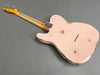 Back view of pink relic electric guitar with worn finish and maple neck on gray background