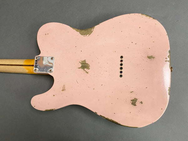 Back view of a worn pink electric guitar body with vintage relic finish and string ferrules, showing neck plate with screws and neck wood grain.