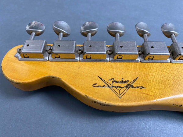 Close-up of vintage Fender Custom Shop guitar headstock with six vintage-style tuning pegs and worn maple wood finish on gray background