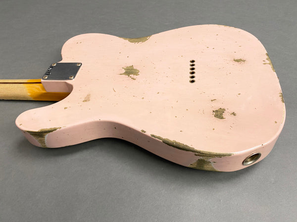 Back of vintage distressed pink electric guitar body with worn paint and string ferrules on a gray background