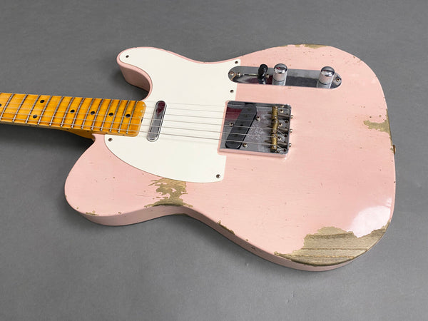 Close-up of worn pink electric guitar with white pickguard, maple neck, and chrome hardware on grey background