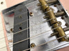 Close-up of Fender Telecaster guitar bridge and single-coil pickup with vintage brass saddles and pat. pend. engraving on chrome plate