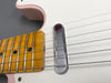 Close-up of vintage electric guitar neck with maple fretboard and chrome pickup on white body with pink accents and six metal strings